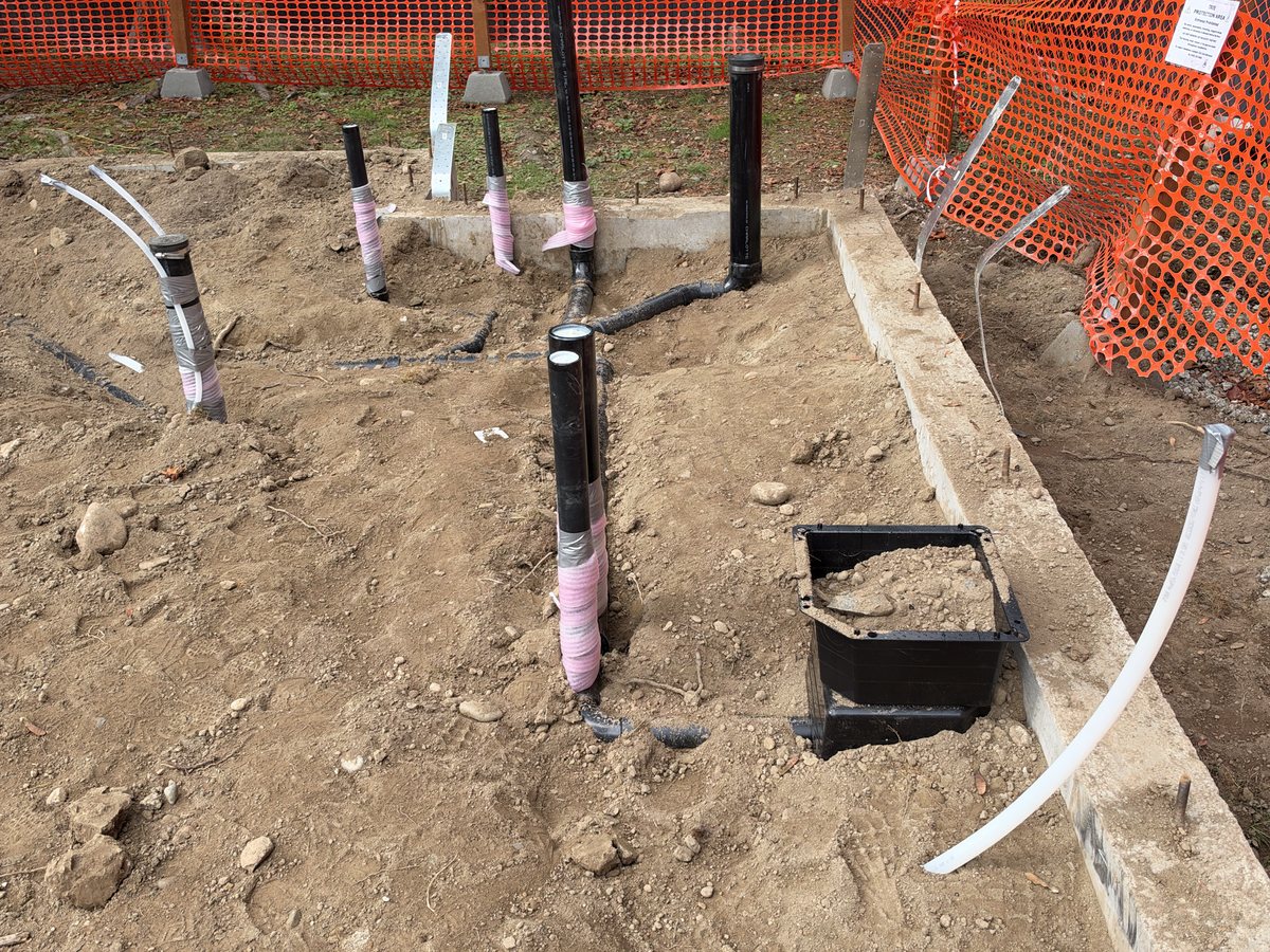 Underground plumbing pipes stubbed up through the gravel base