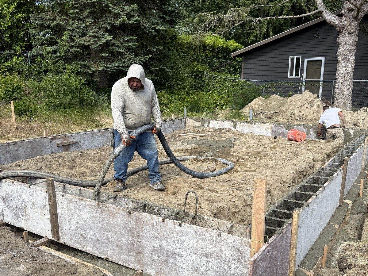 Crew pouring concrete into the stem wall forms